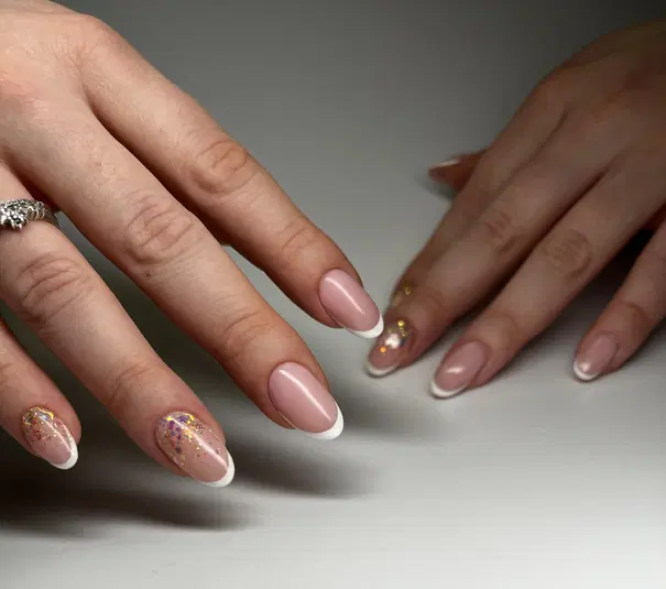  Elegancki manicure francuski z różowymi paznokciami i białymi końcówkami, ozdobiony brokatem na jednym paznokciu. 