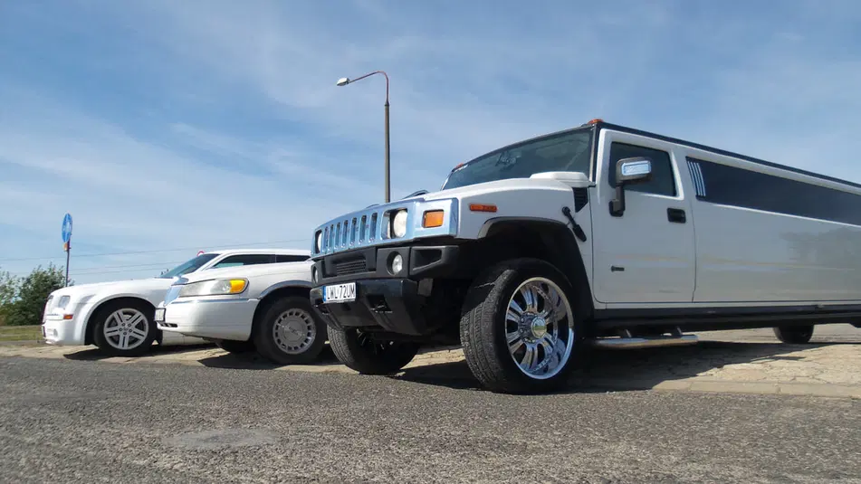  Białe limuzyny Hummer i Lincoln na tle nieba, luksusowe samochody na parkingu. 