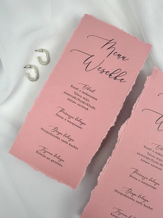 Różowe menu weselne z eleganckimi napisami i srebrnymi kolczykami na białym tle