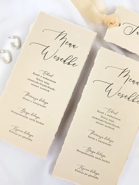 Menu weselne z eleganckim designem, zawierające dania takie jak rosół z makaronem, talerz mięs, dorsz z warzywami, niespodzianka szefa kuchni oraz kolacja po góralsku. Stylowy układ tekstu na kremowym papierze.