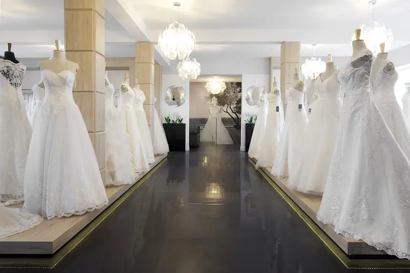  Wnętrze salonu sukien ślubnych z manekinami prezentującymi różne modele białych sukien w eleganckim otoczeniu. 