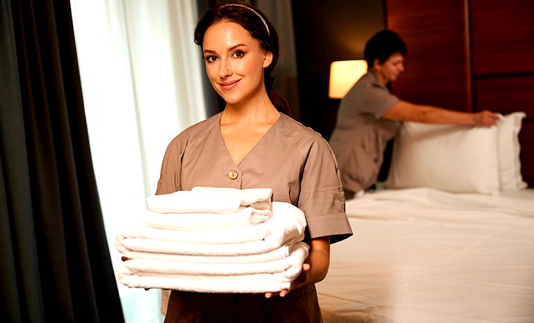  Personel hotelowy z białymi ręcznikami przygotowuje pokój dla gości. 