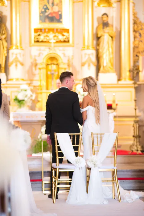 Para młoda podczas ceremonii ślubnej w kościele, eleganckie dekoracje i złote akcenty.