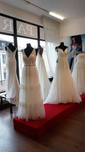  Suknie ślubne na manekinach w salonie, eleganckie białe suknie z koronkowymi detalami, wystawa mody ślubnej, nowoczesne wzory ślubne. 