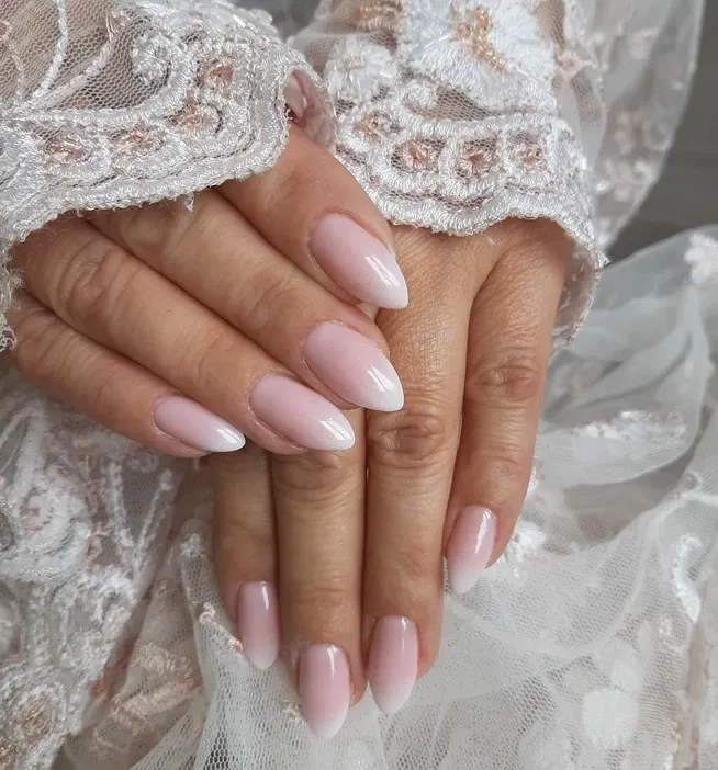 Elegancki manicure ślubny, dłonie z paznokciami w delikatnym różowym ombre, koronka.