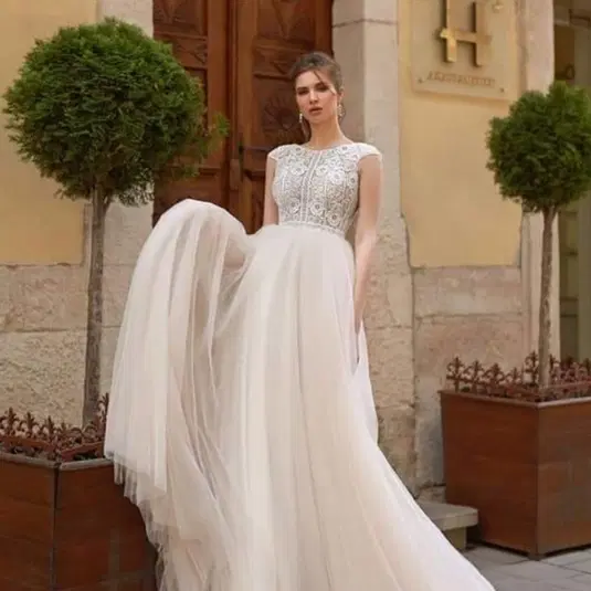 Elegancka suknia ślubna z koronkowym gorsetem i tiulową spódnicą na tle stylowej architektury. 