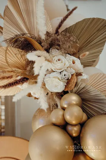  Bukiet suszonych kwiatów z białymi różami i złotymi balonami dekoracyjnymi, styl boho, elegancka aranżacja kwiatowa, dekoracja wnętrz, naturalne elementy, artystyczna kompozycja florystyczna. 