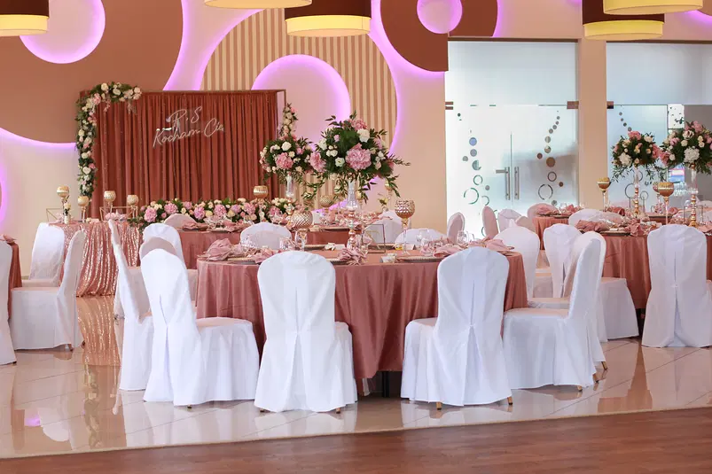  Elegancka sala weselna udekorowana różowymi i białymi elementami, okrągłe stoły z kwiatami, nakryte na przyjęcie. 