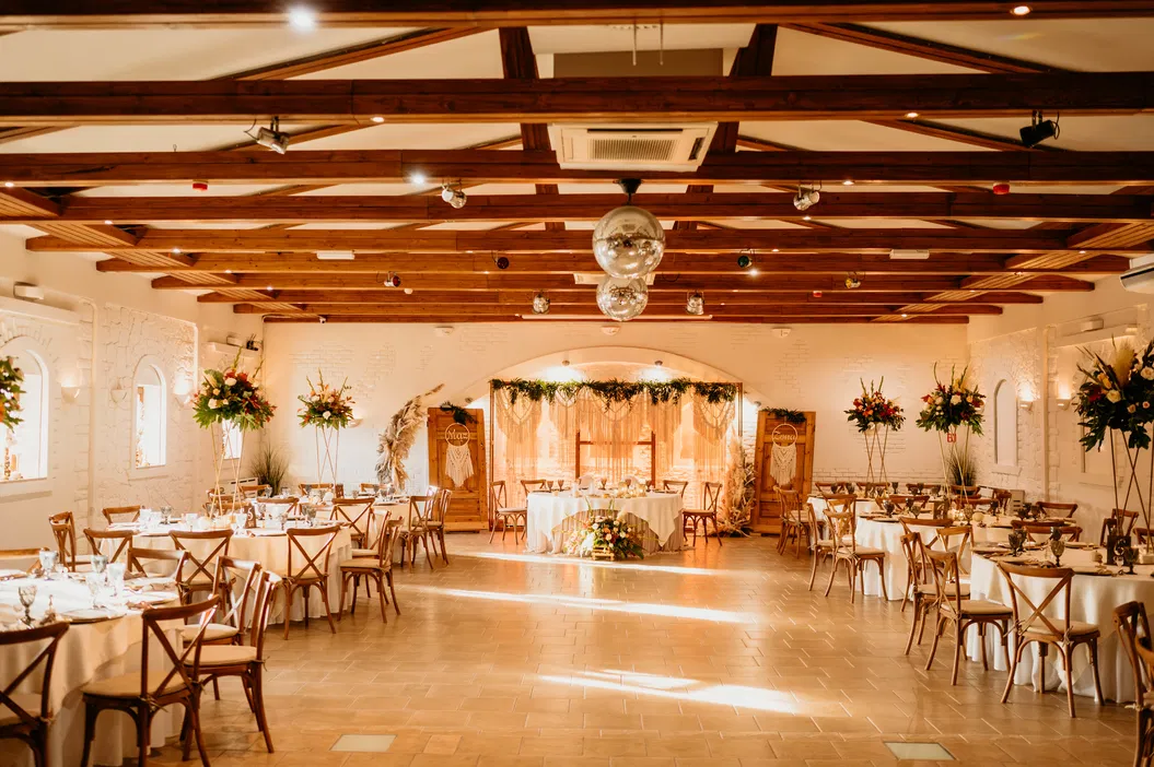 Elegancka sala weselna z dekoracjami kwiatowymi i stołami przygotowanymi na przyjęcie.