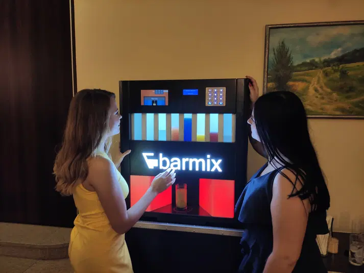  Dwie osoby obsługujące automat do napojów Barmix, wieczorne oświetlenie. 