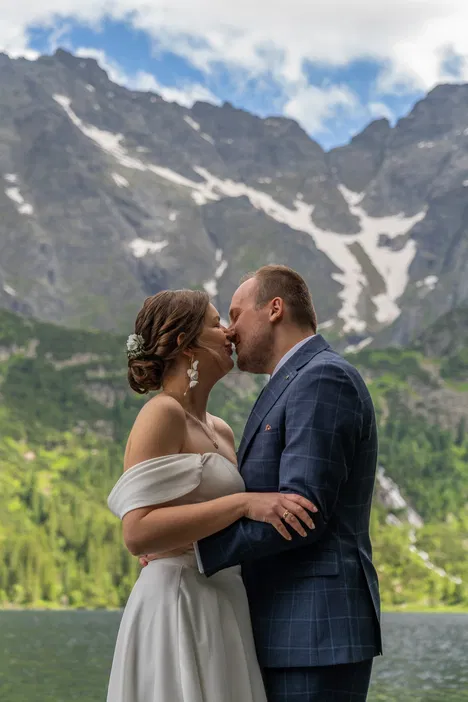 Para młoda w górach, romantyczne zdjęcie ślubne na tle malowniczych szczytów i jeziora, lato, przyroda.