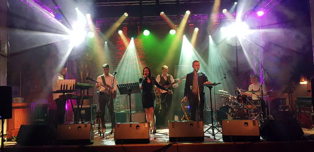  Zespół muzyczny na scenie, koncert na żywo, występ z oświetleniem scenicznym, muzycy grający na instrumentach, wokalista i keyboardzista. 