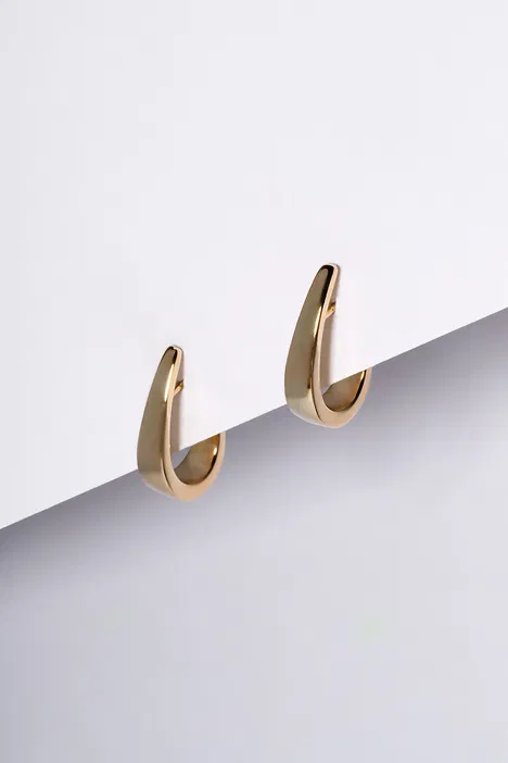 Złote kolczyki w minimalistycznym stylu na białym tle, elegancka biżuteria dla kobiet.