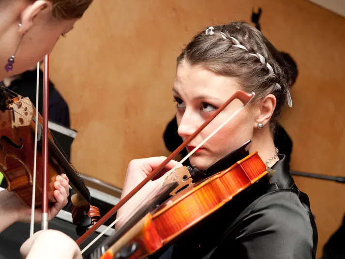  Muzyczka grająca na skrzypcach podczas koncertu, zbliżenie na instrument i skupioną twarz 