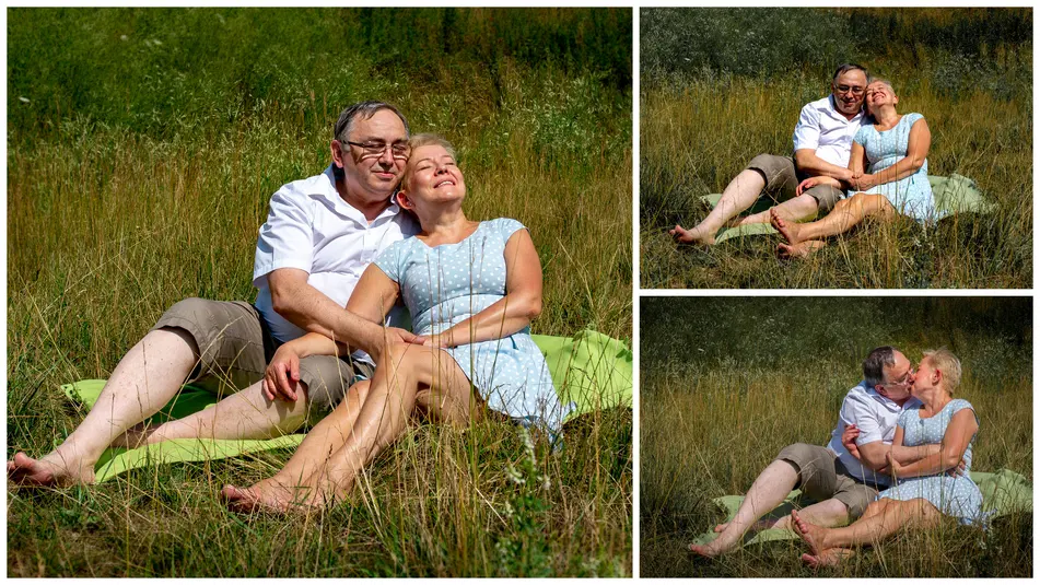  Para odpoczywająca na kocu w letnim słońcu na polanie, uśmiechnięci i zrelaksowani, siedzą blisko siebie w otoczeniu zieleni. 
