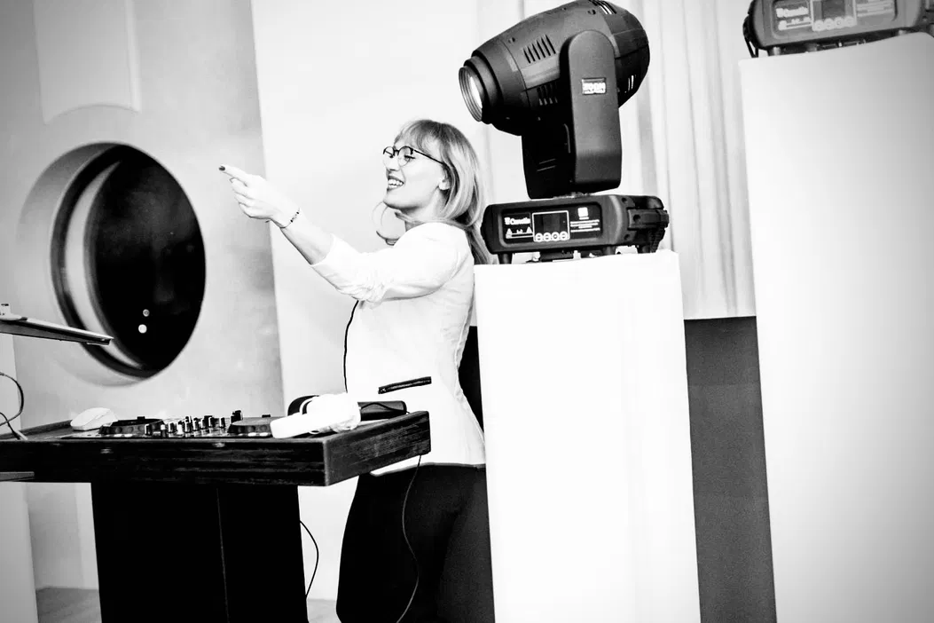 Nieznana kobieta pracująca przy konsolecie DJ-skiej i sprzęcie oświetleniowym w stylowym studio.