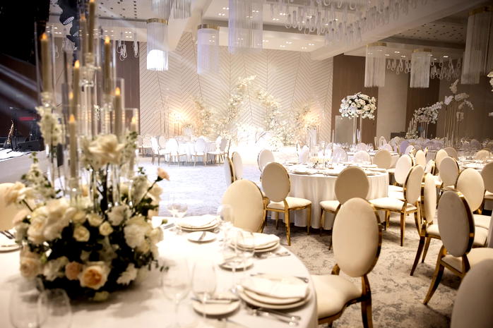  Luksusowa sala weselna z eleganckimi dekoracjami, białymi krzesłami i ozdobami kwiatowymi, idealne miejsce na wystawne przyjęcie weselne. 