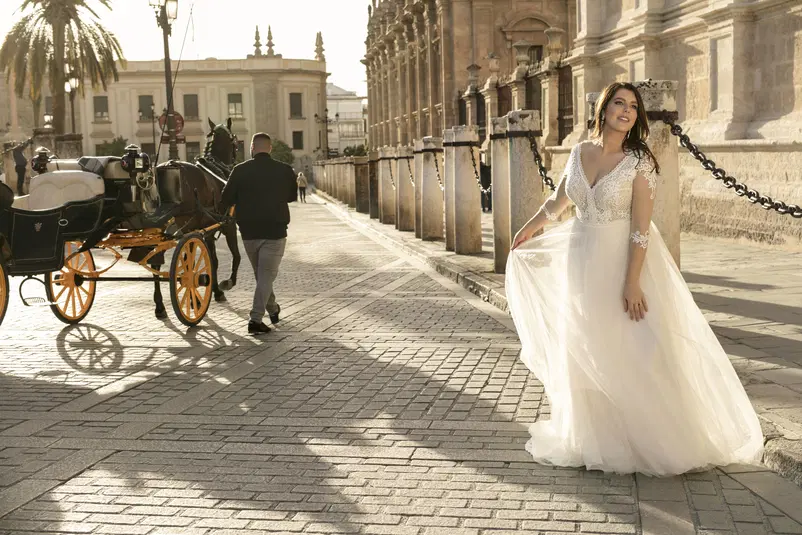  Panna młoda w eleganckiej sukni ślubnej na tle zabytkowego miasta, z powozem konnym w tle, fotografia w stylu vintage. 