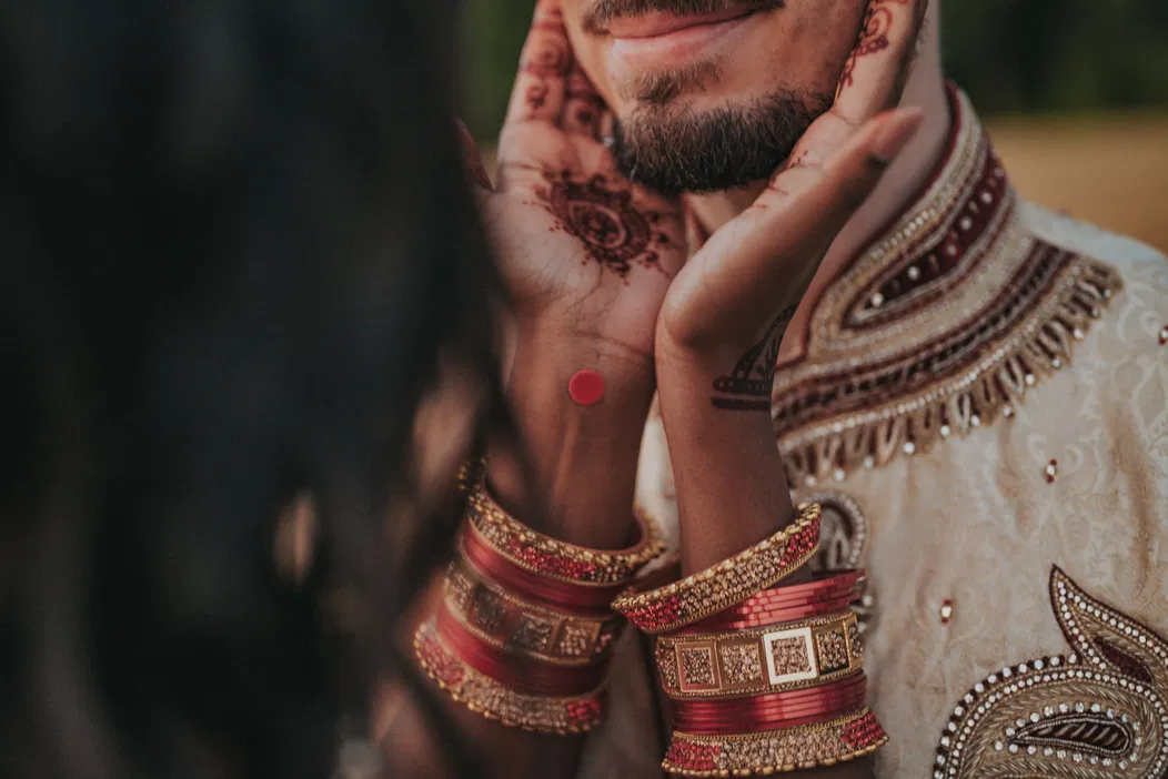 Para w tradycyjnych strojach indyjskich z biżuterią i mehendi na dłoniach, fotografia ślubna.