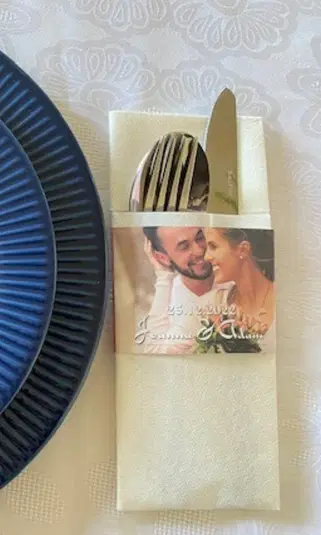  Stół weselny z zastawą, personalizowanym serwetnikiem ze sztućcami i zdjęciem pary młodej, data 25.12.2022. 