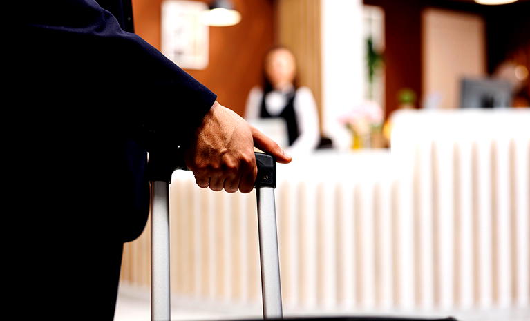  Osoba z walizką przy recepcji hotelu. 