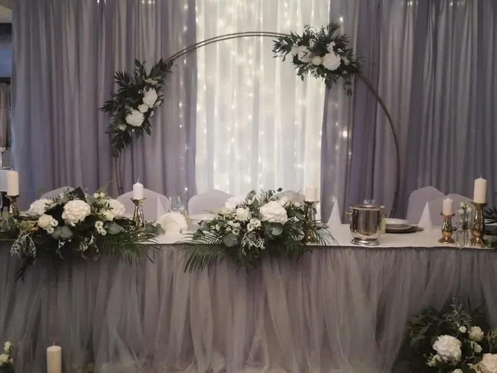  Elegancka dekoracja stołu weselnego z kwiatami, świecami i świetlnymi tkaninami na tle. 