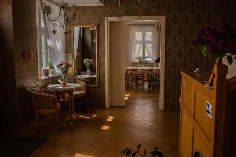  Elegancka restauracja z drewnianymi meblami i kwiatami w wazonach, przestronne wnętrze z dużymi oknami i delikatnymi zasłonami tworzy przytulną atmosferę idealną na romantyczną kolację. 