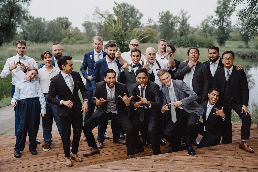 Grupa mężczyzn ubranych w garnitury podczas sesji na świeżym powietrzu, pozy humorystyczne, wesele, fotografia ślubna.
