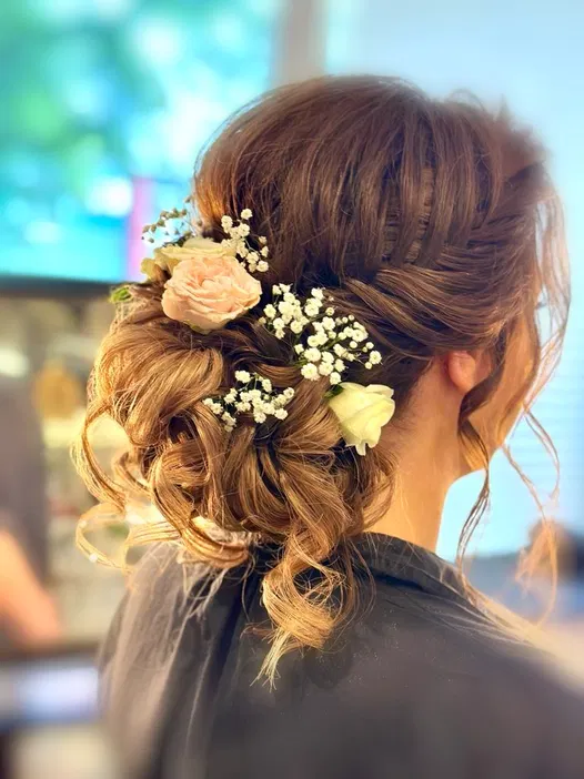 Elegancka fryzura ślubna z kwiatowymi ozdobami w stylu boho, romantyczne upięcie z różami i gipsówką.
