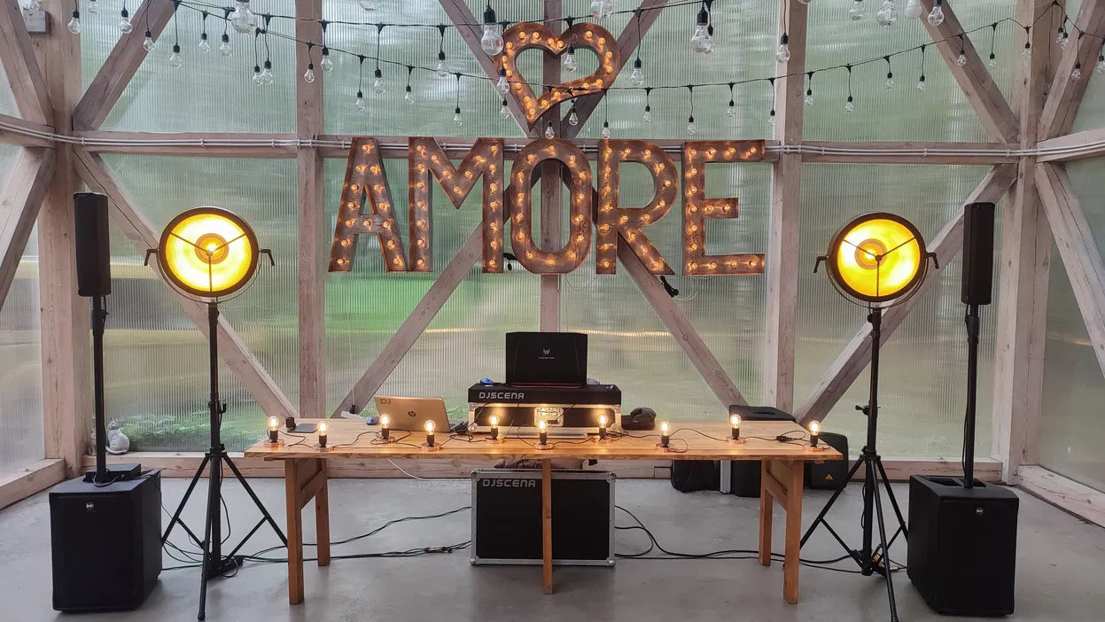 Oświetlona scena DJ z dużym napisem AMORE i dekoracjami świetlnymi, idealna na romantyczne wydarzenie.