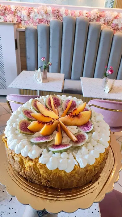 Tort ozdobiony figami i brzoskwiniami na złotej paterze w eleganckiej kawiarni z kwiatowym wystrojem.