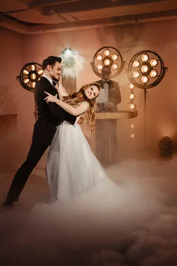  Taniec pary młodej na weselu w eleganckim otoczeniu z efektem dymu i ciepłym oświetleniem w tle. 