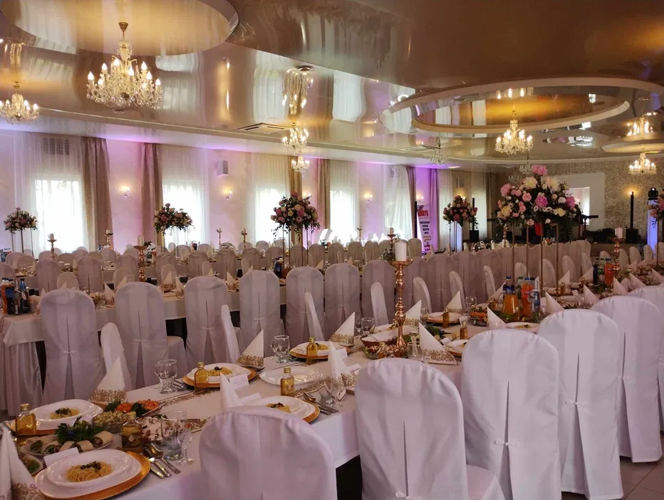 Elegancka sala weselna z dekoracjami kwiatowymi i nakrytymi stołami, gotowa na przyjęcie weselne.