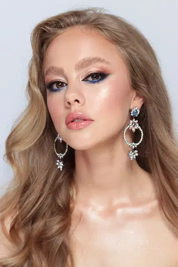  Nieznana kobieta z długimi blond włosami, elegancko umalowana, w dużych, ozdobnych kolczykach - portret studyjny. 