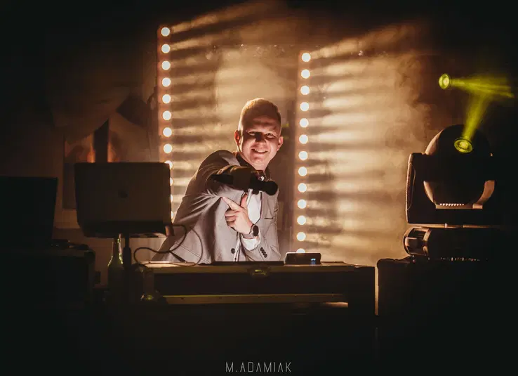  DJ na scenie z mikrofonem i efektownym oświetleniem, muzyka na żywo, impreza klubowa. 