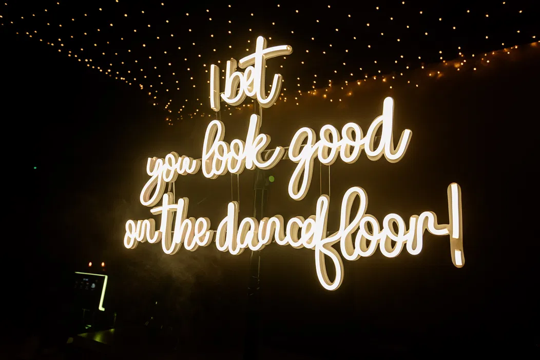 Neonowy napis I bet you look good on the dancefloor na tle ciemnych świateł