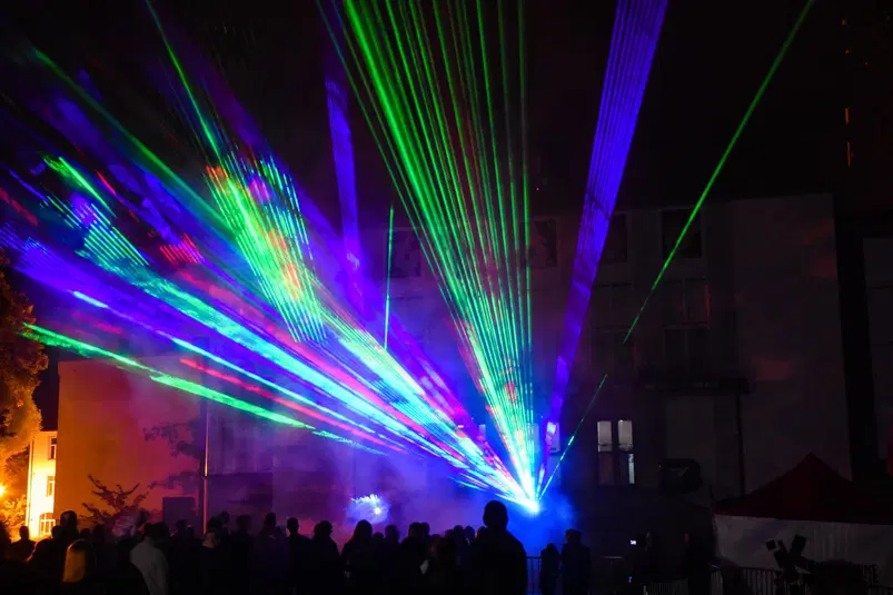  Widowiskowy pokaz laserów w nocy, kolorowe światła i tłum ludzi na tle miejskiej architektury. 