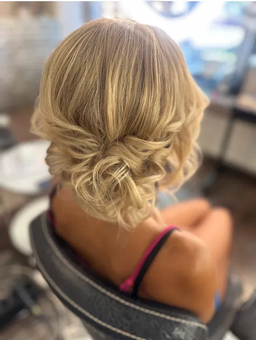 Blond włosy upięte w elegancki kok, fryzura na specjalne okazje, stylizacja włosów w salonie, delikatne loki.