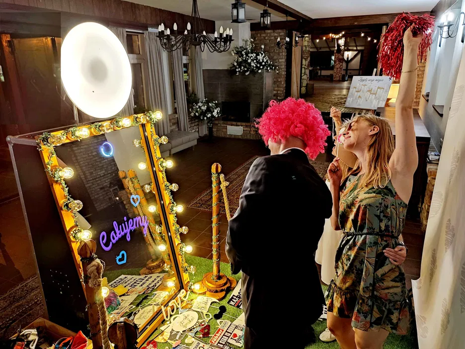 Mirror photo booth at a lively event with people wearing colorful costumes, bright lights, and decorations.