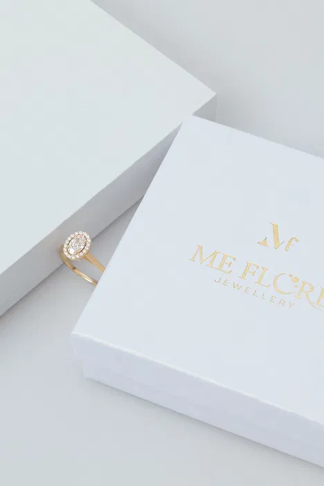 Złoty pierścionek z diamentem na białym tle w pudełku Me Flore Jewellery.