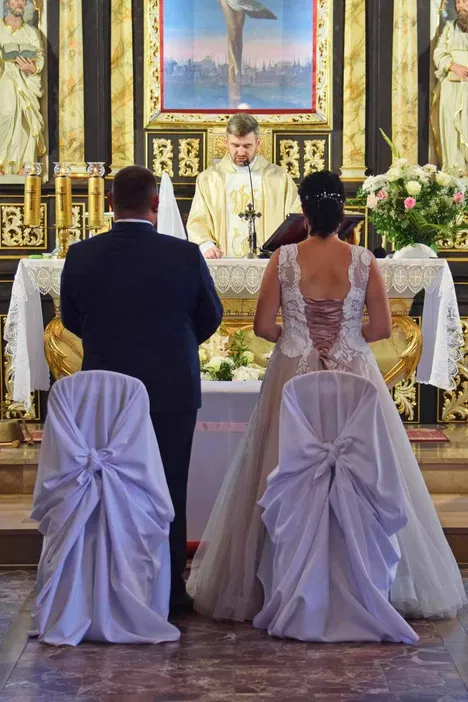 Para młoda podczas ceremonii ślubnej w kościele, ksiądz prowadzi mszę przed ołtarzem.