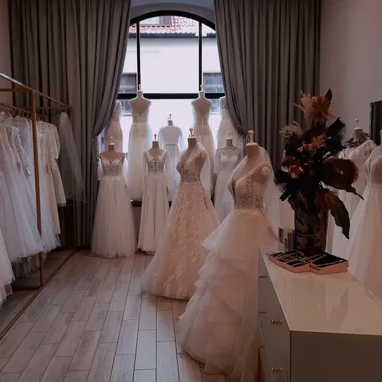  Ekskluzywny salon sukni ślubnych, różnorodne modele na manekinach przy oknie, eleganckie koronki i tiule 