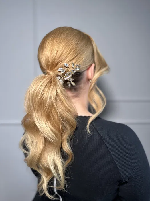 Blond włosy upięte w elegancki koński ogon z ozdobną spinką, fryzura na specjalne okazje.