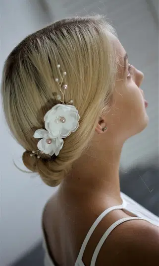  Blondynka z eleganckim upięciem włosów ozdobionym białymi kwiatami i perłami, widok z profilu na stylową fryzurę na wyjątkowe okazje. 