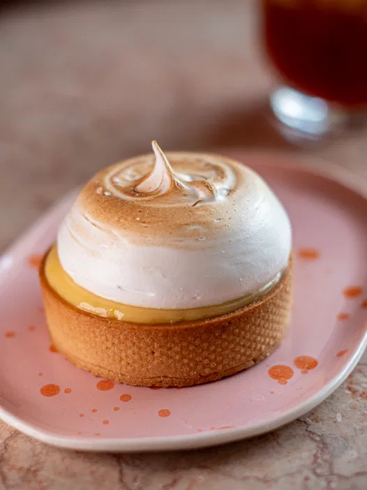 <p>Tarta cytrynowa z bezą na różowym talerzu, deser w stylu francuskim</p>