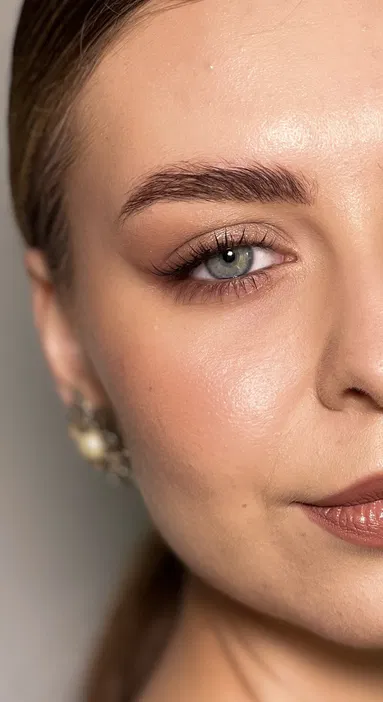 Zbliżenie na twarz z jednym okiem, zadbanymi brwiami i eleganckim makijażem podkreślającym usta oraz oko, idealne dla artykułów o technikach makijażu i pielęgnacji skóry.