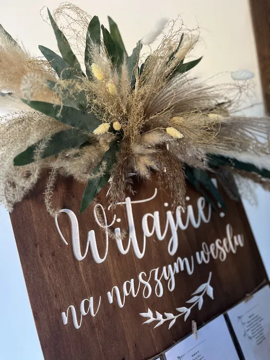 Powitalna tablica weselna z suszonymi kwiatami i liśćmi na drewnie
