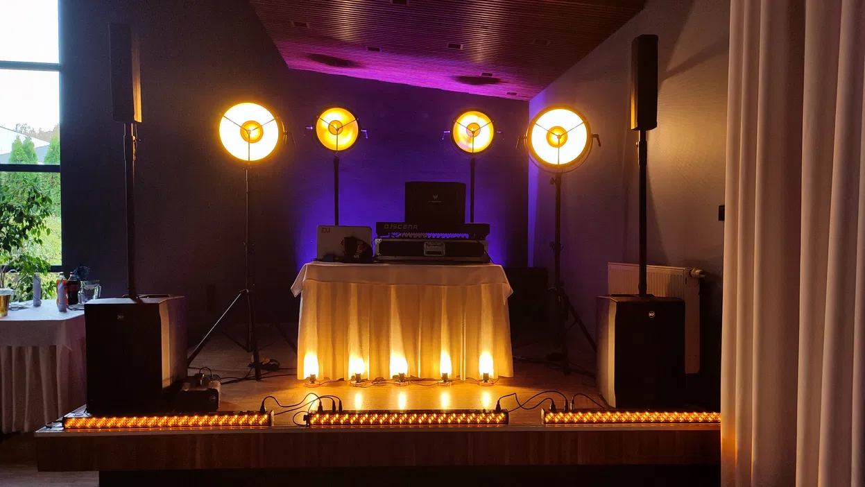 Profesjonalne oświetlenie sceniczne na weselu z reflektorami i sprzętem DJ-skim.