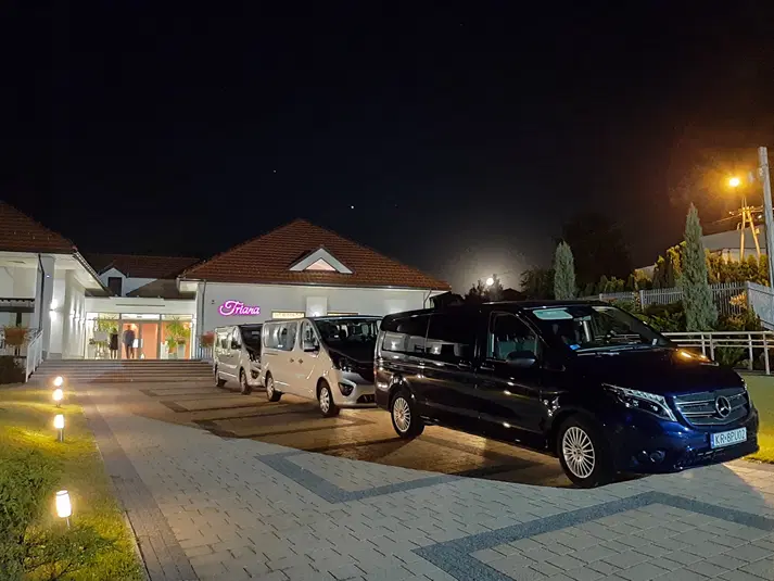  Parking nocą przed budynkiem z napisem Griana i zaparkowane samochody. 