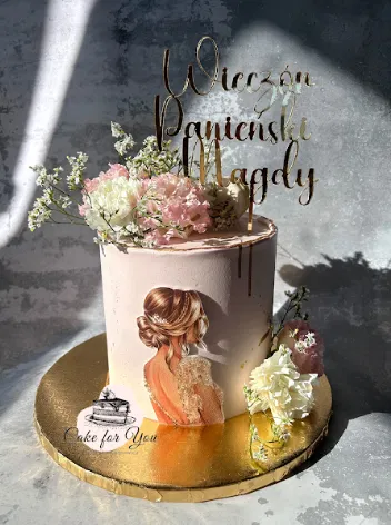 Tort na wieczór panieński z dekoracją kwiatową i spersonalizowanym napisem Wieczór Panieński Magdy, ozdobiony obrazkiem eleganckiej kobiety, na złotej podstawie.